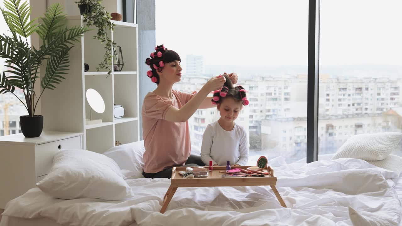 妈妈和女儿用卷发器做一个时髦的发型。视频下载