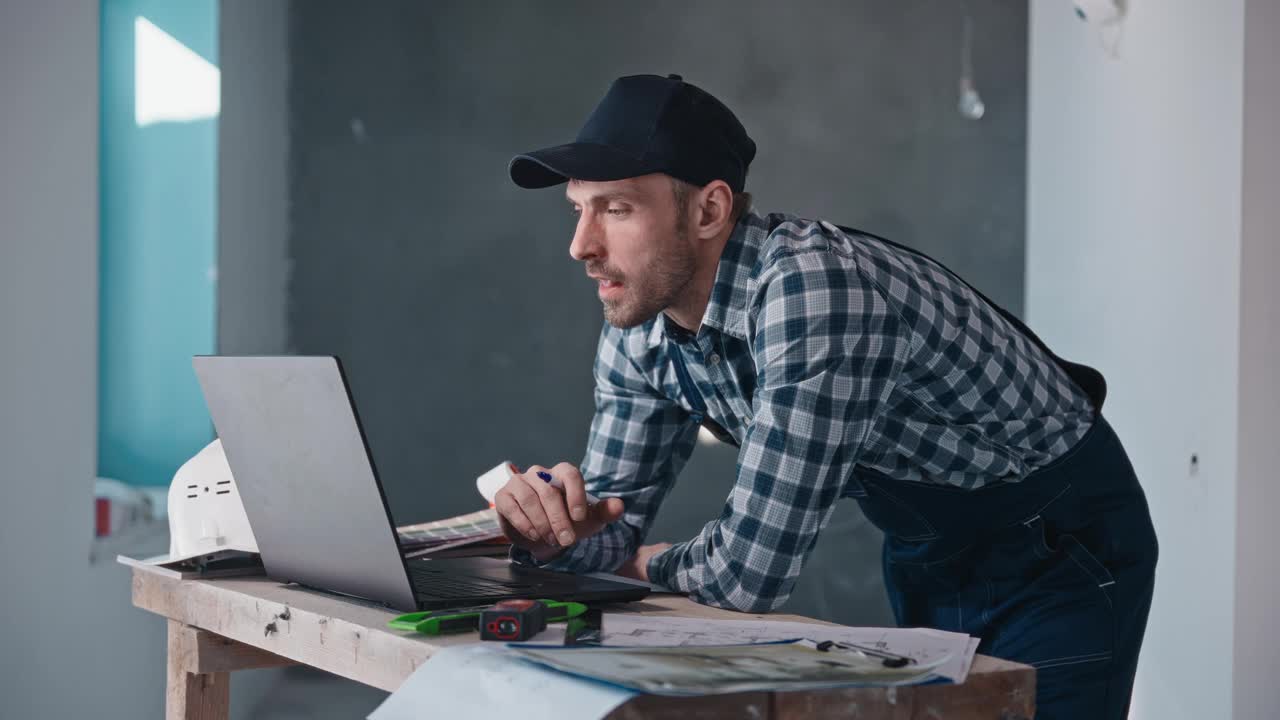 一个男人拿着一台笔记本电脑站在桌子前视频下载
