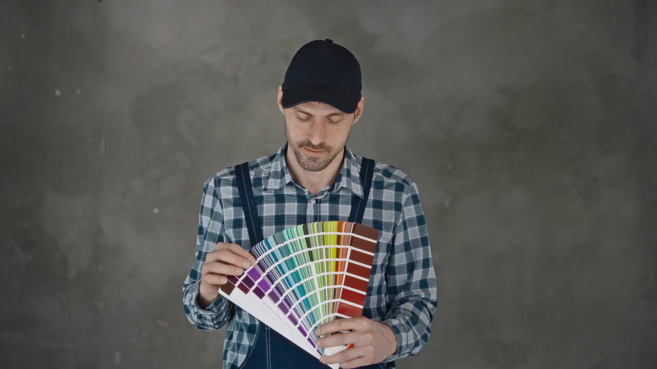 一名男性建筑工人手里拿着调色板，选择正在施工的公寓墙壁的颜色。室内装修视频下载