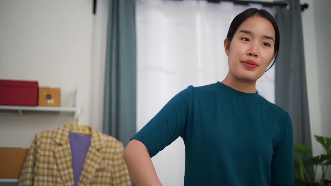年轻的女企业主站在手机上直播卖衣服，为顾客把衣服装进盒子里。视频下载