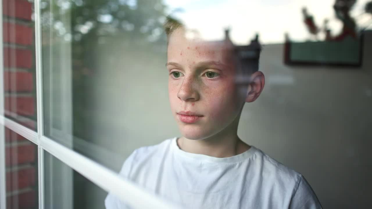 患有自闭症的白人男孩，站在窗边捂着耳朵视频下载