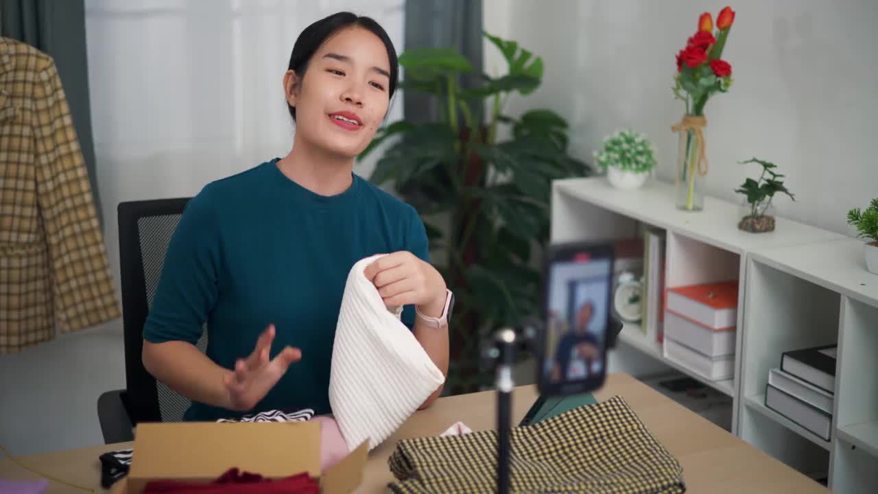 年轻女企业主在家用手机直播卖衣服。视频下载