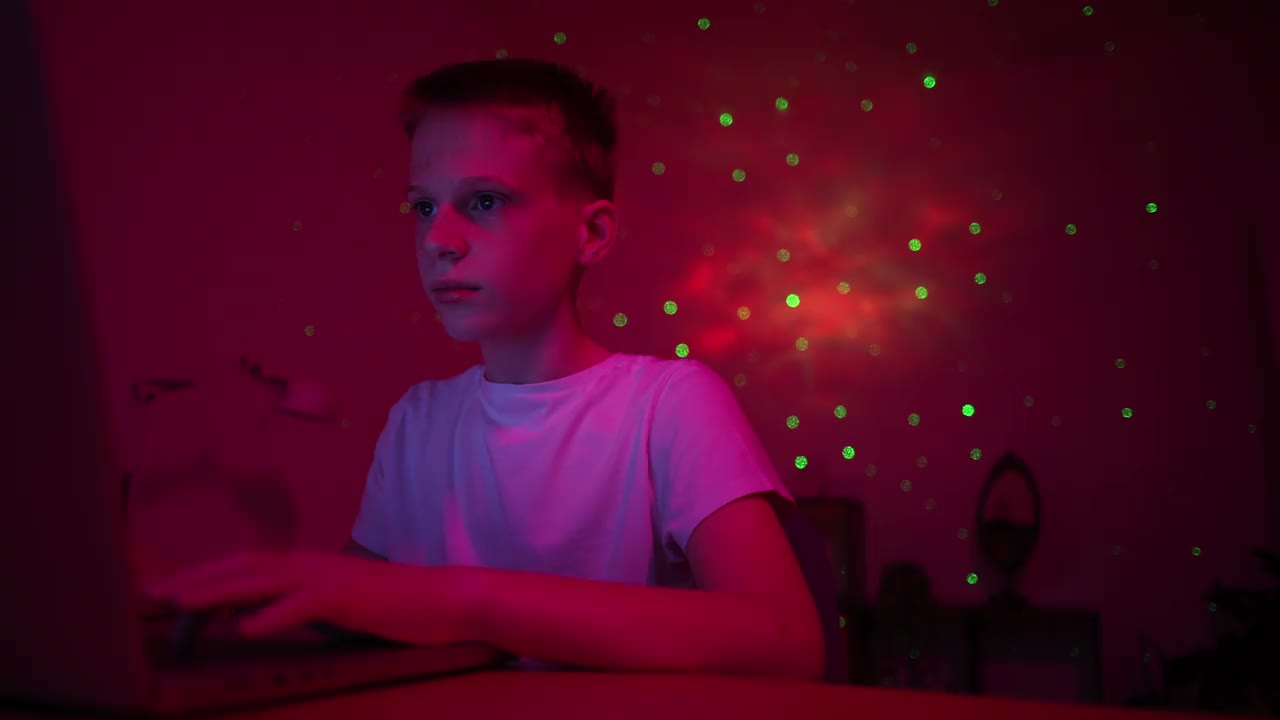 一个白人男孩的侧视图，在一间紫色灯光的房间里玩电子游戏视频下载