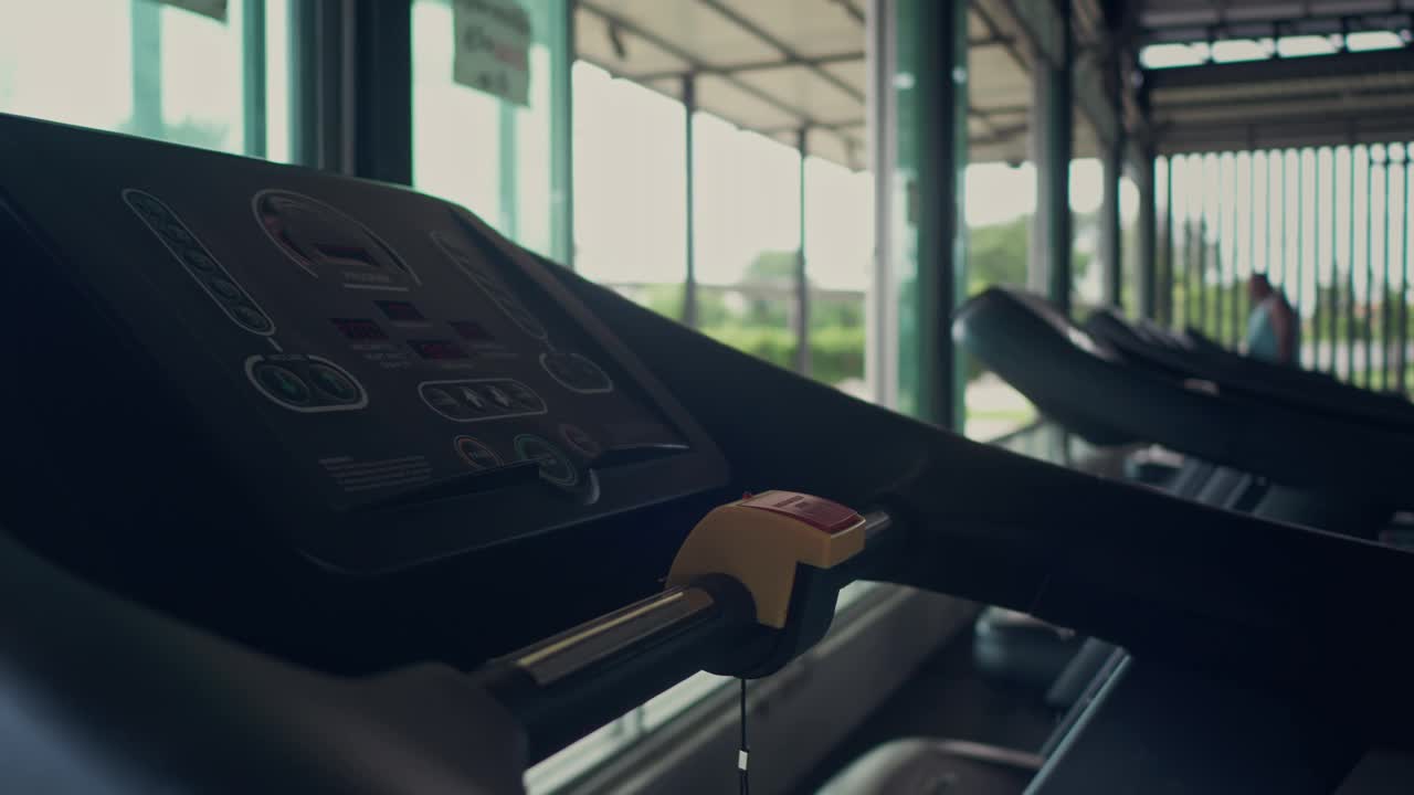 一名亚洲妇女在健身房里的跑步机上散步和锻炼视频下载