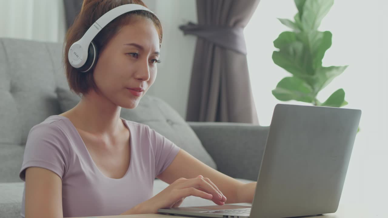 一位戴着耳机的女士正在使用笔记本电脑视频下载