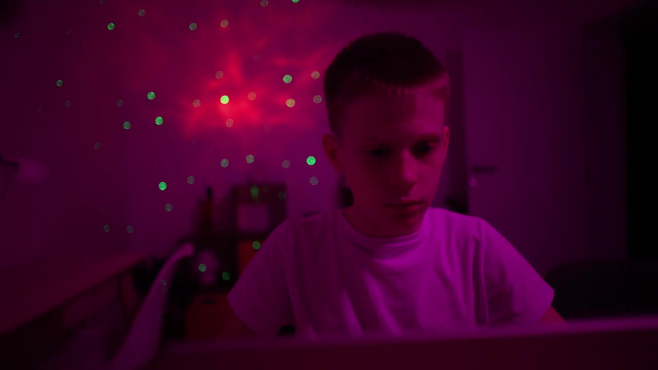 一个白人男孩，在一间紫色灯光的房间里玩电子游戏视频下载