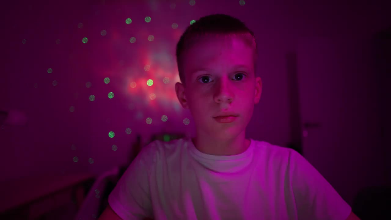 一个沉迷于视频游戏的白人男孩的画像，在一间紫色灯光的房间里视频下载