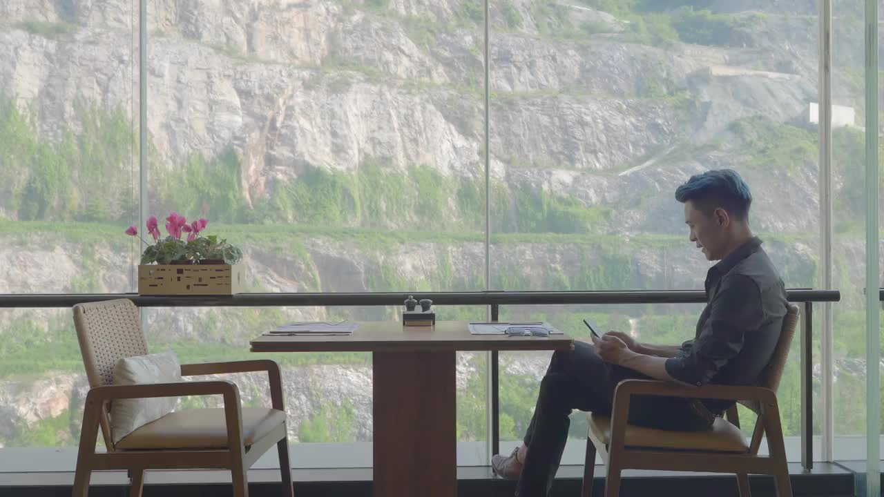 一名亚洲男子在餐厅用手机视频下载