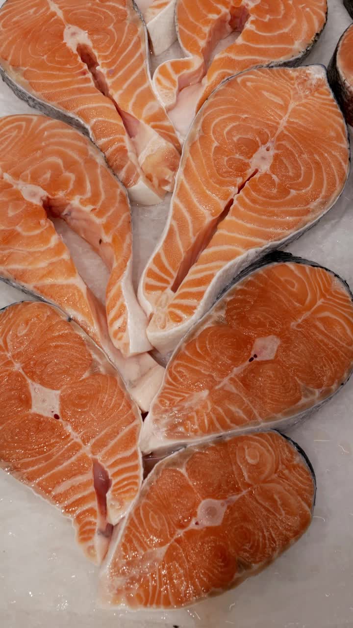 垂直格式。新鲜的鲑鱼排放在超市的冰上。杂货店里一个柜台上的红色鲜鱼特写。美味健康的海鲜，冷冻视频下载