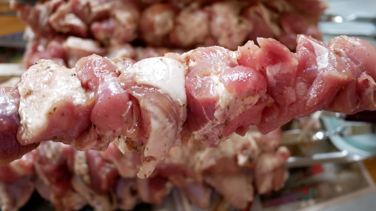 烤羊肉串前把生肉串在烤肉串上。切碎的生猪肉。视频下载