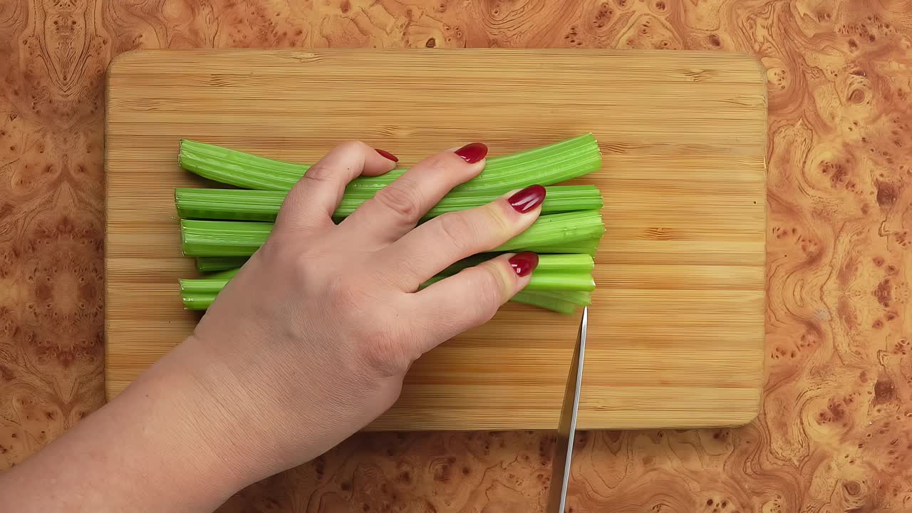 小刀在木板上把绿芹菜切成小块视频下载