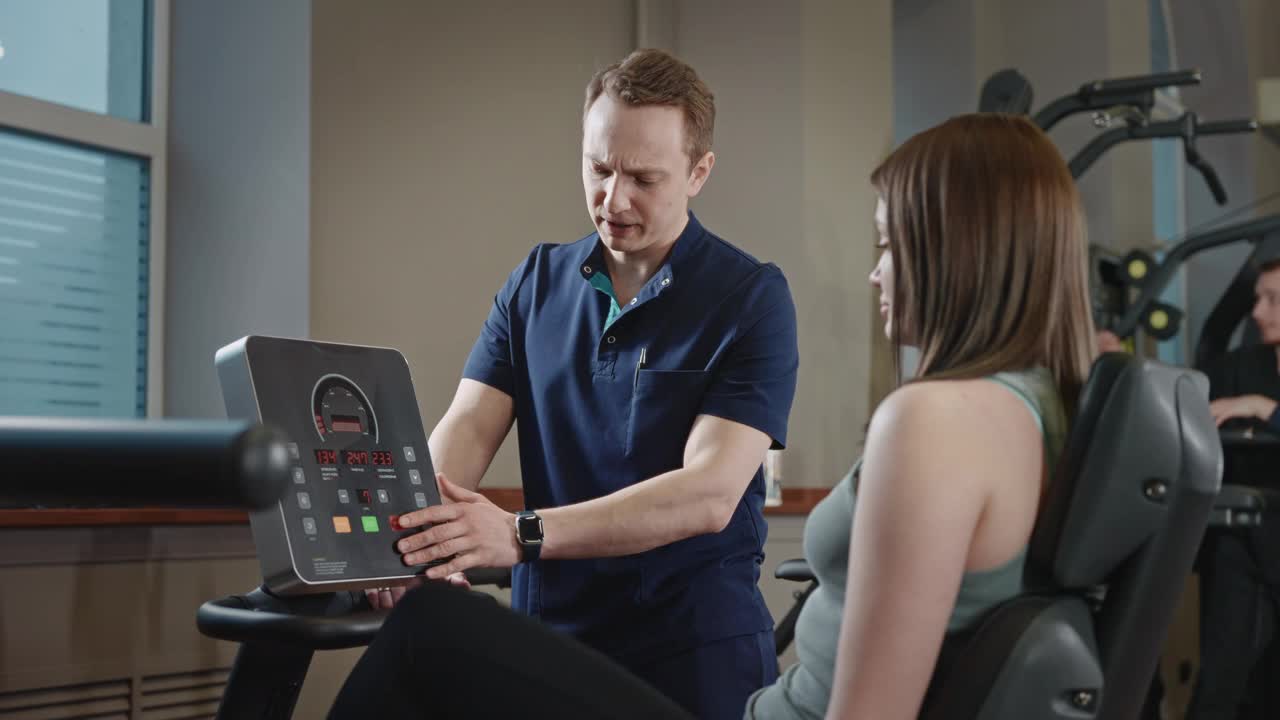 在一个专门的健身房里，病人的运动康复。一名男性物理治疗师监测康复运动的表现。视频下载