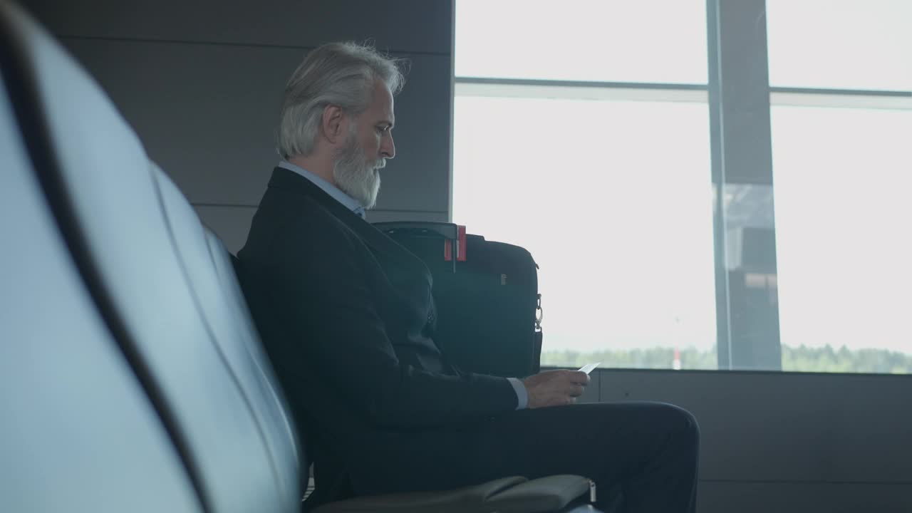 成熟商人在机场候机楼使用智能手机视频下载