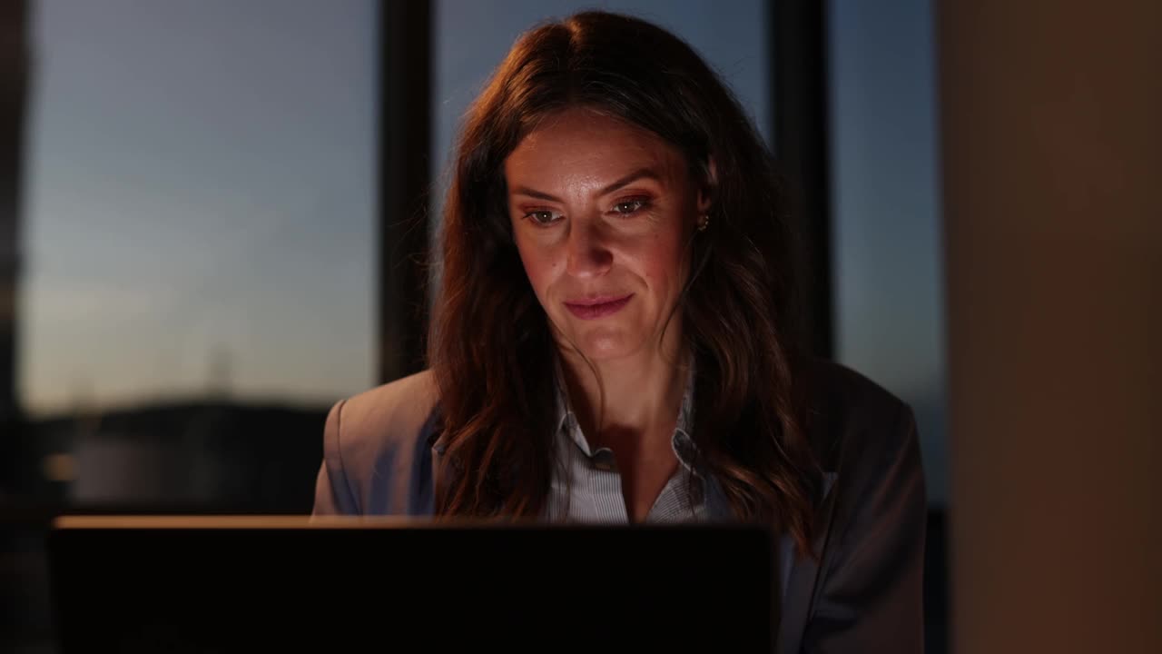 晚上在办公室用笔记本电脑工作的女商人视频下载