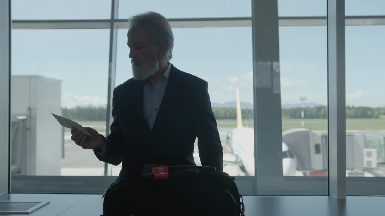 成熟的商人在机场候机楼拿着登机牌视频下载