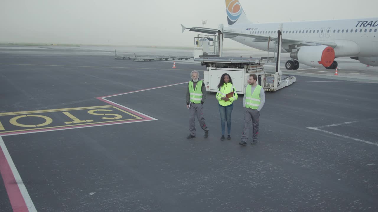 机场地勤人员在停机坪上散步和讨论视频下载