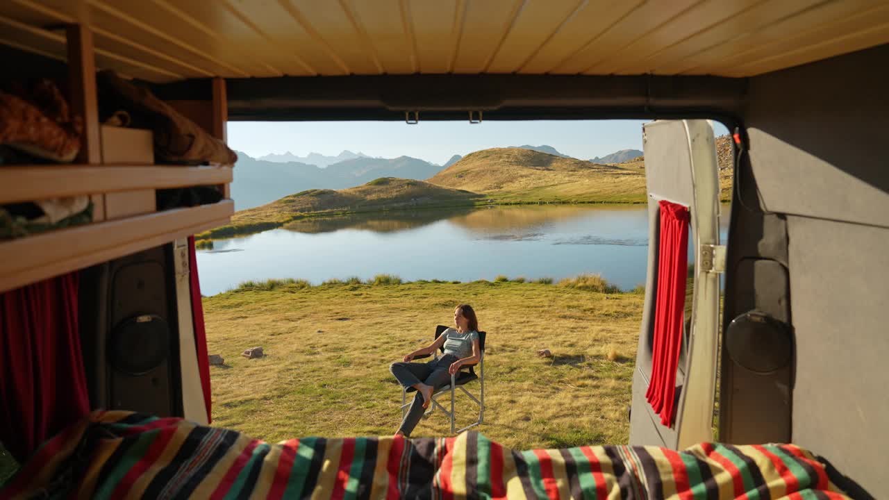 一名妇女开着露营车在山间湖边休息视频下载
