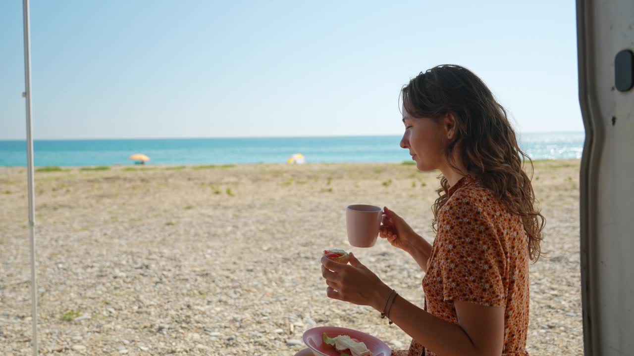 一个女人坐在海滩上，吃着当地法国产的三明治视频下载