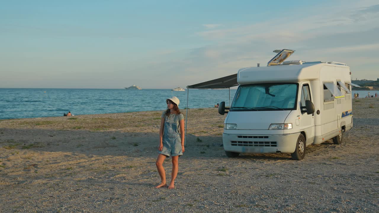 站在沙滩上露营车旁边的一个快乐的女人视频下载