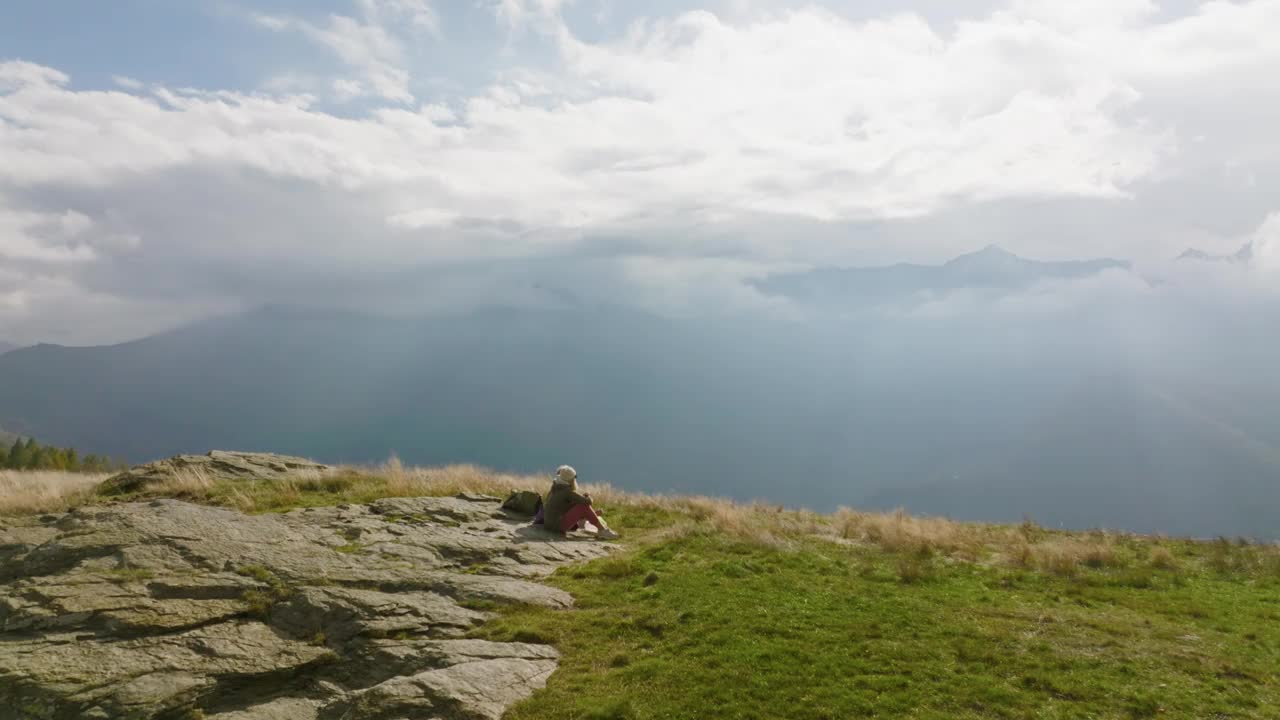 一对徒步旅行的夫妇在一片生机勃勃的绿色草地上休息的鸟瞰图视频下载