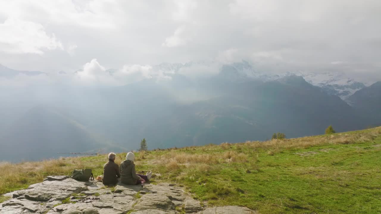 一对徒步旅行的夫妇在一片生机勃勃的绿色草地上休息的鸟瞰图视频下载