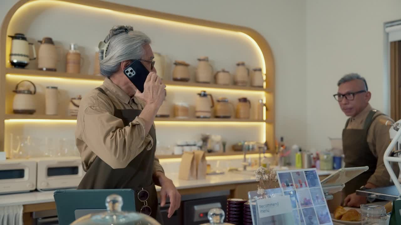 咖啡店老板用手机接听顾客的订单。视频下载
