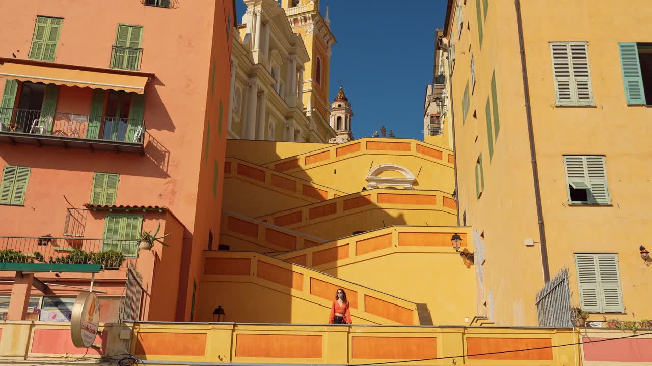 一名女子站在法国里维埃拉芒通镇的橙色楼梯上视频下载