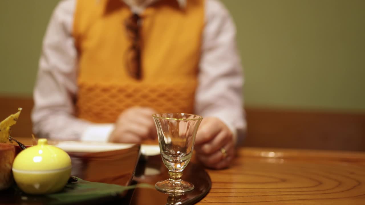 老年夫妇在传统日本餐厅倒日本酒的特写视频下载