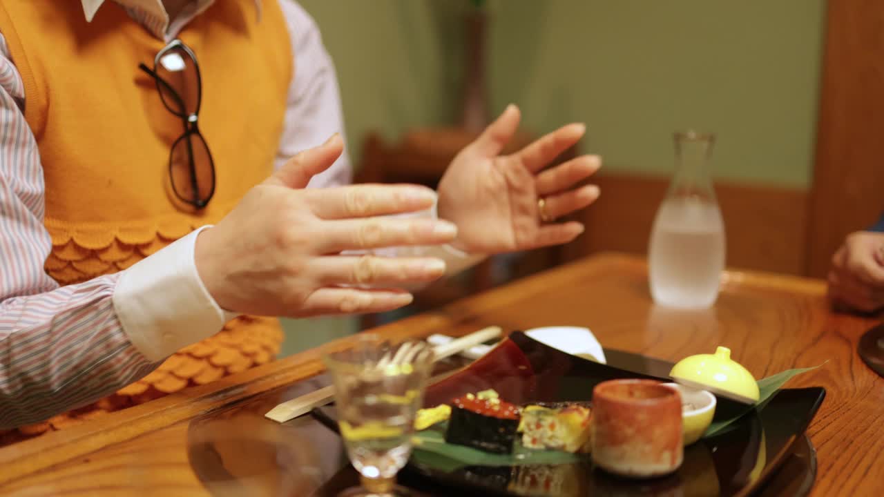 老年夫妇在传统日本餐厅吃晚餐的特写——手的特写视频下载