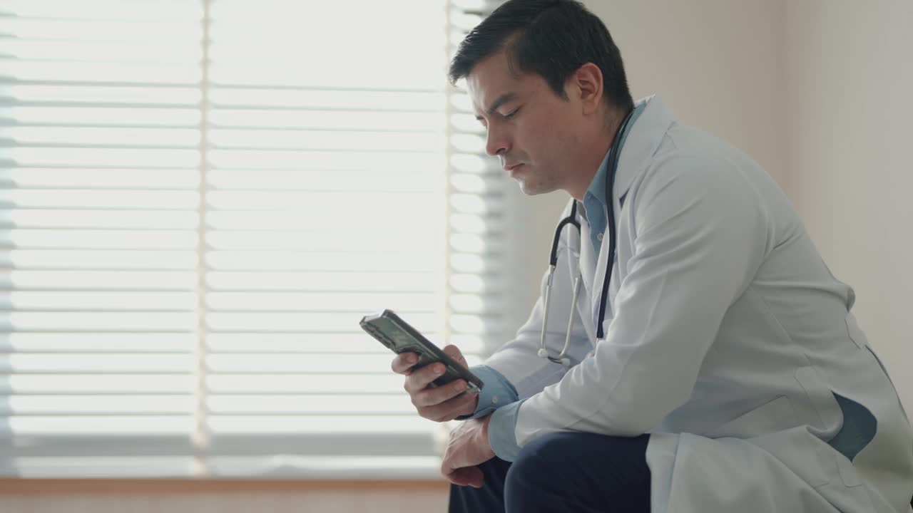 成熟的医疗保健提供者在诊所:肖像的自信医生使用电话在医疗实践。视频下载
