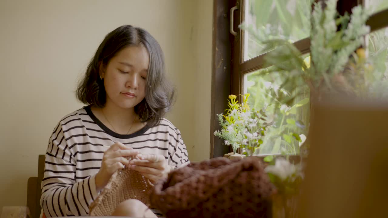 年轻女子在一个休闲的家里休息和享受钩针编织。视频下载