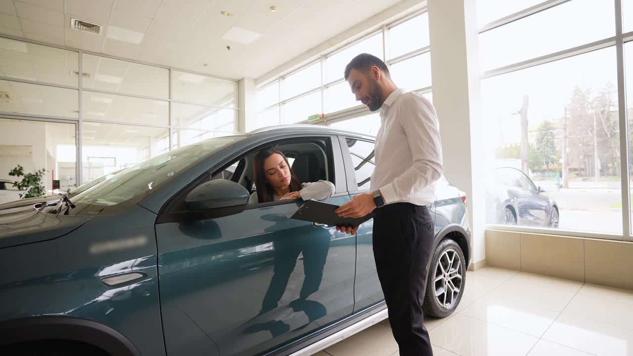 销售人员在汽车经销店帮助妇女选择豪华汽车视频下载