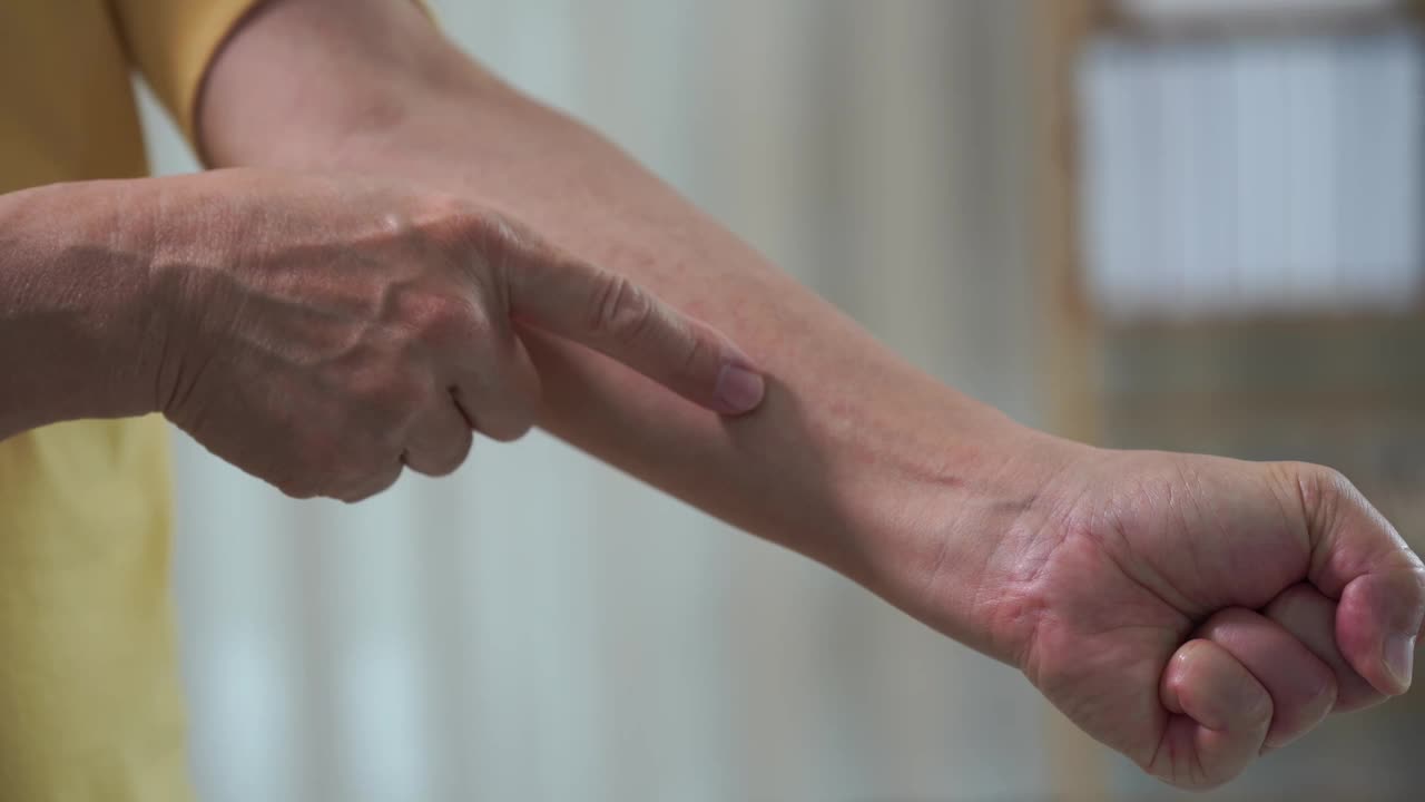 一个亚洲老人身体疼痛的特写视频。肌肉疼痛无力，手臂和脚踝疼痛保健概念视频下载