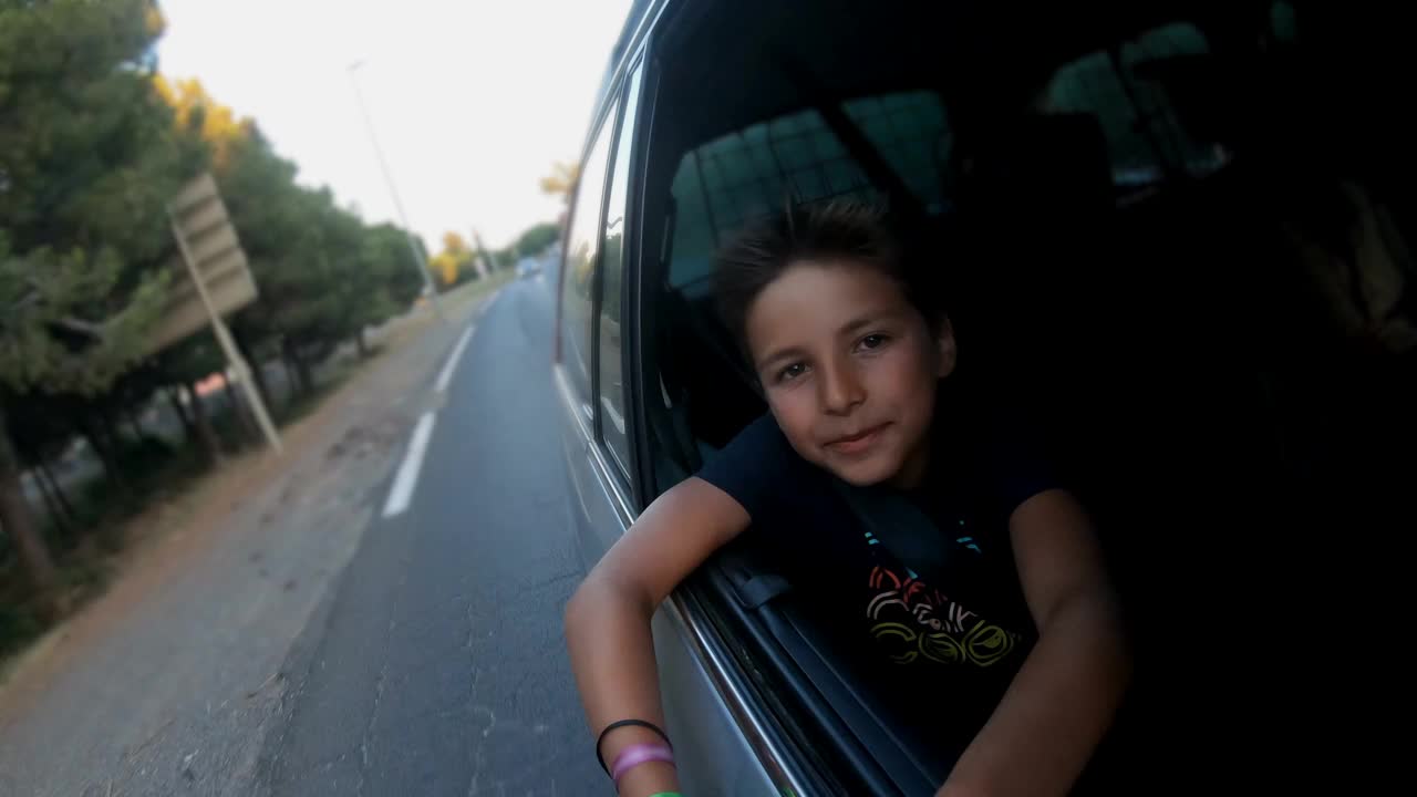 男孩坐在汽车的副驾驶座位上，看着开着的窗户视频下载