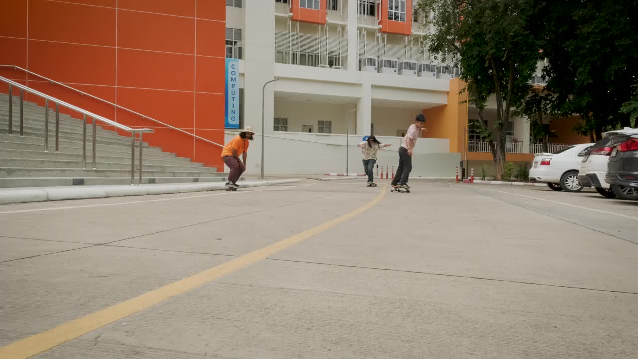 一小群年轻的亚洲朋友的滑板手喜欢在城市的户外街道上玩滑板视频下载