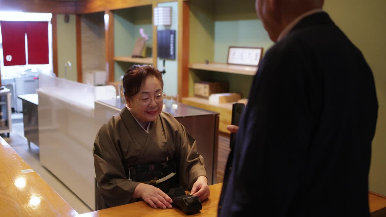 一名男子在传统日本餐厅用智能手机付款视频下载