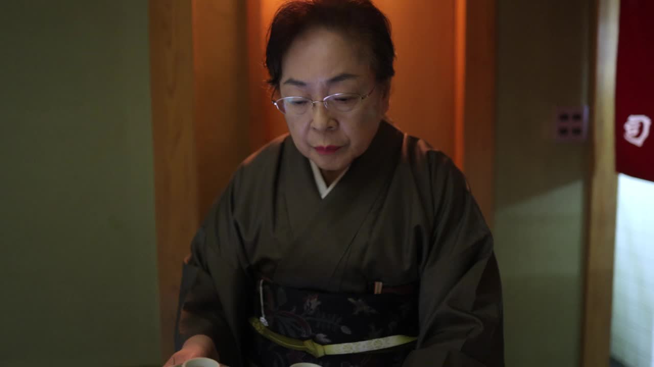 传统日本餐馆的资深女老板正在为顾客提供晚餐——慢镜头视频下载