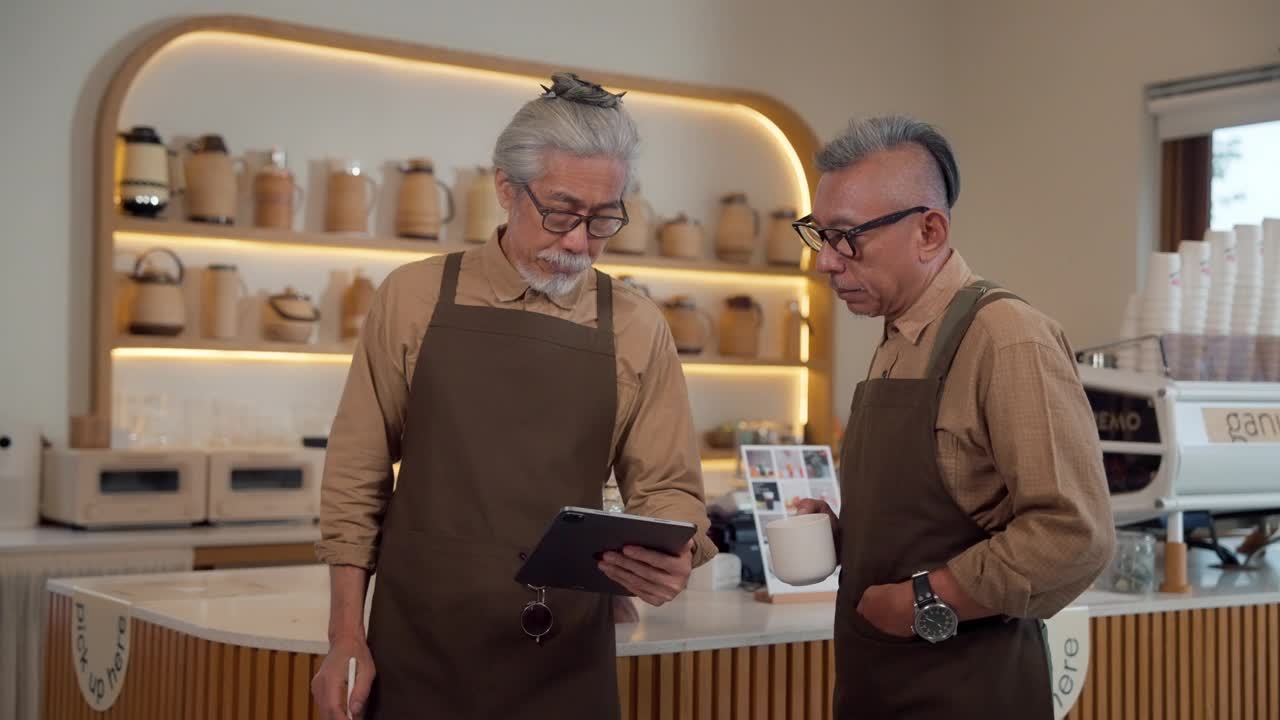 两名服务员在咖啡厅里用平板电脑讨论网上菜单视频下载