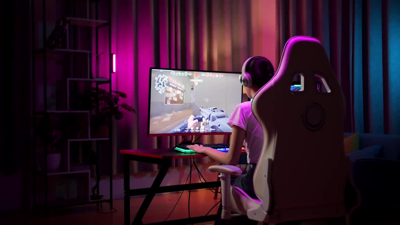 兴奋的亚洲少女玩家庆祝胜利和跳舞，同时玩电脑上的视频游戏，射击在线视频游戏视频下载
