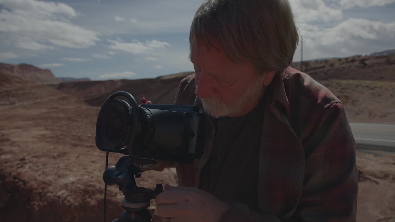 在美国犹他州托里的沙漠上，一个人在三脚架上调整相机的特写视频下载