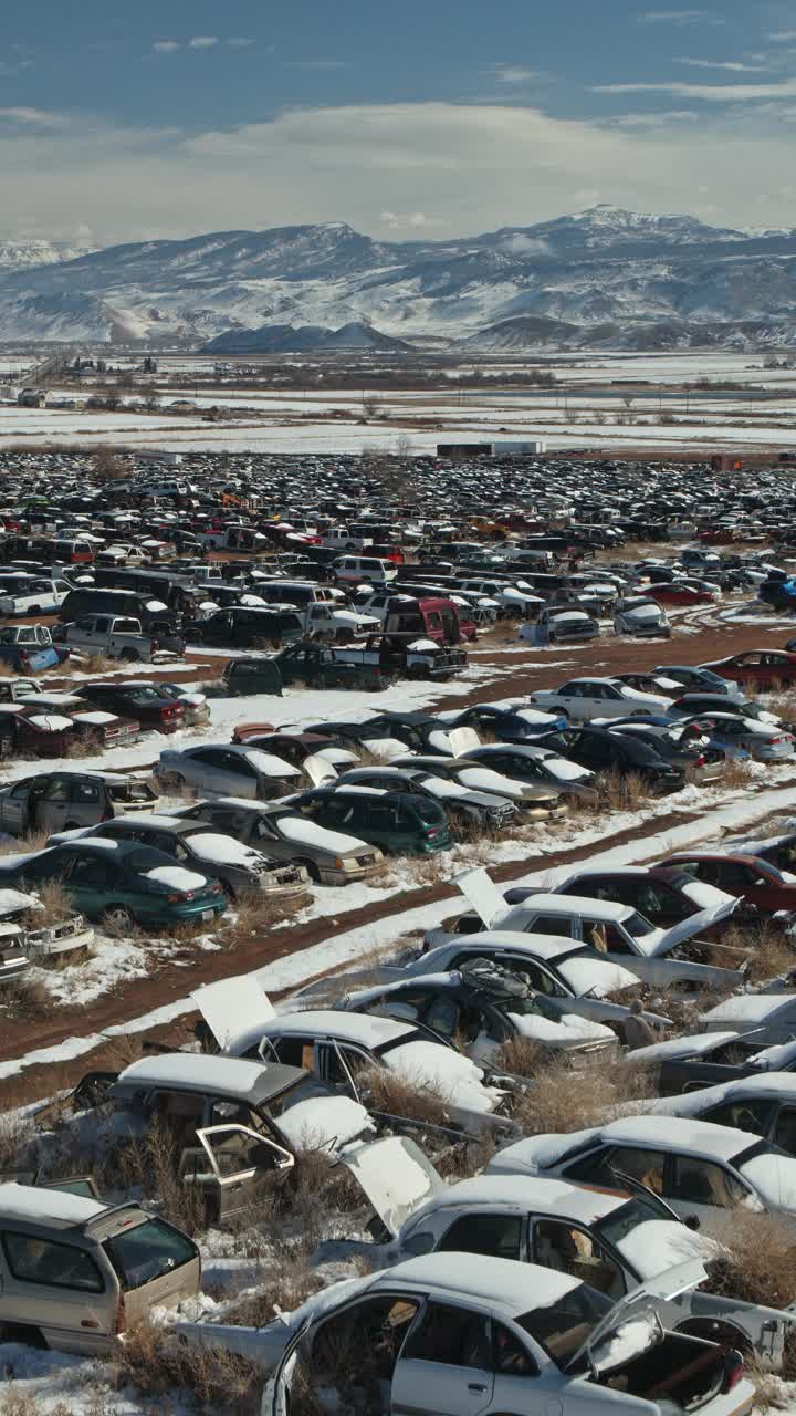 在山脉附近的垃圾场的一排排打捞车的空中立交视图-垂直视频/奥罗拉，犹他州，美国视频下载