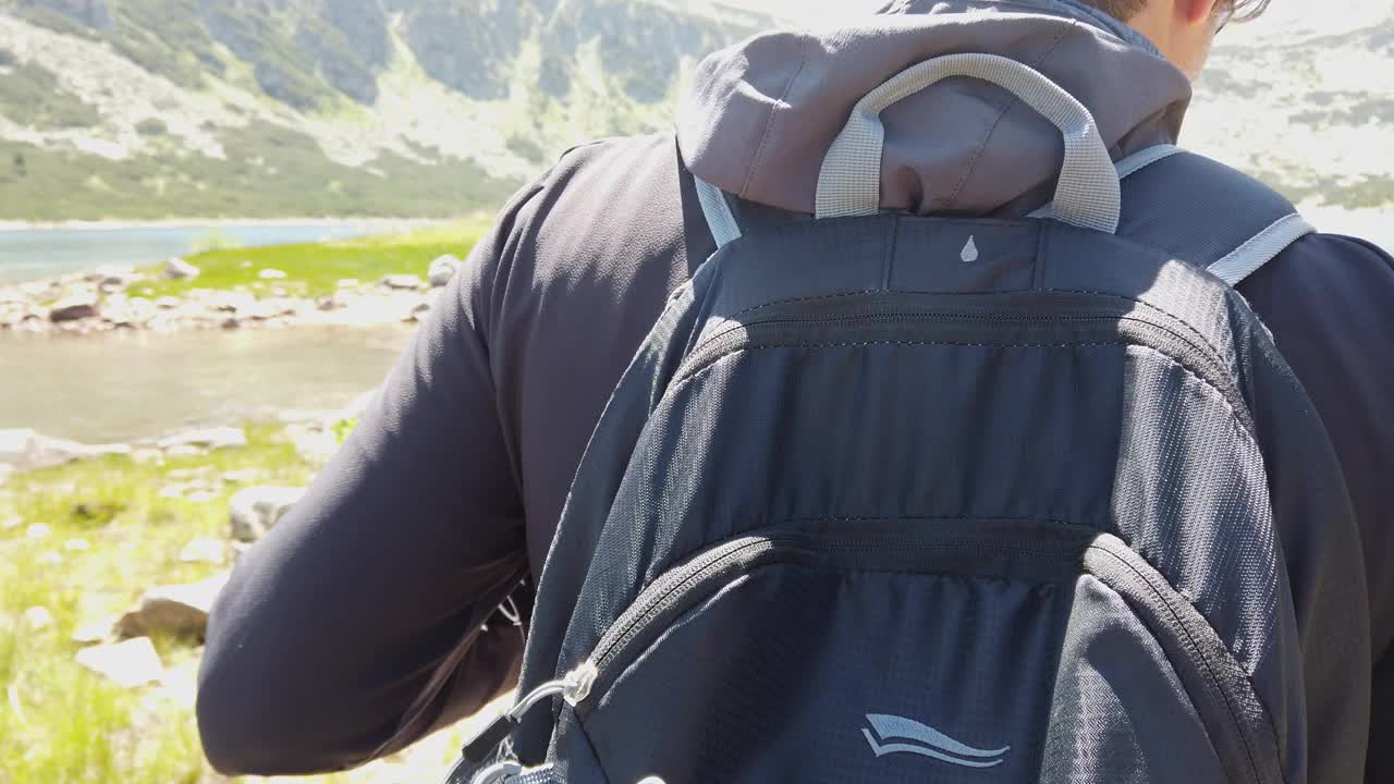 一个男人在湖边背包旅行的后景视频下载