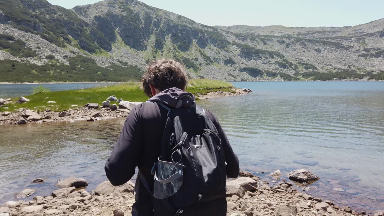 男徒步旅行者站在湖边视频下载