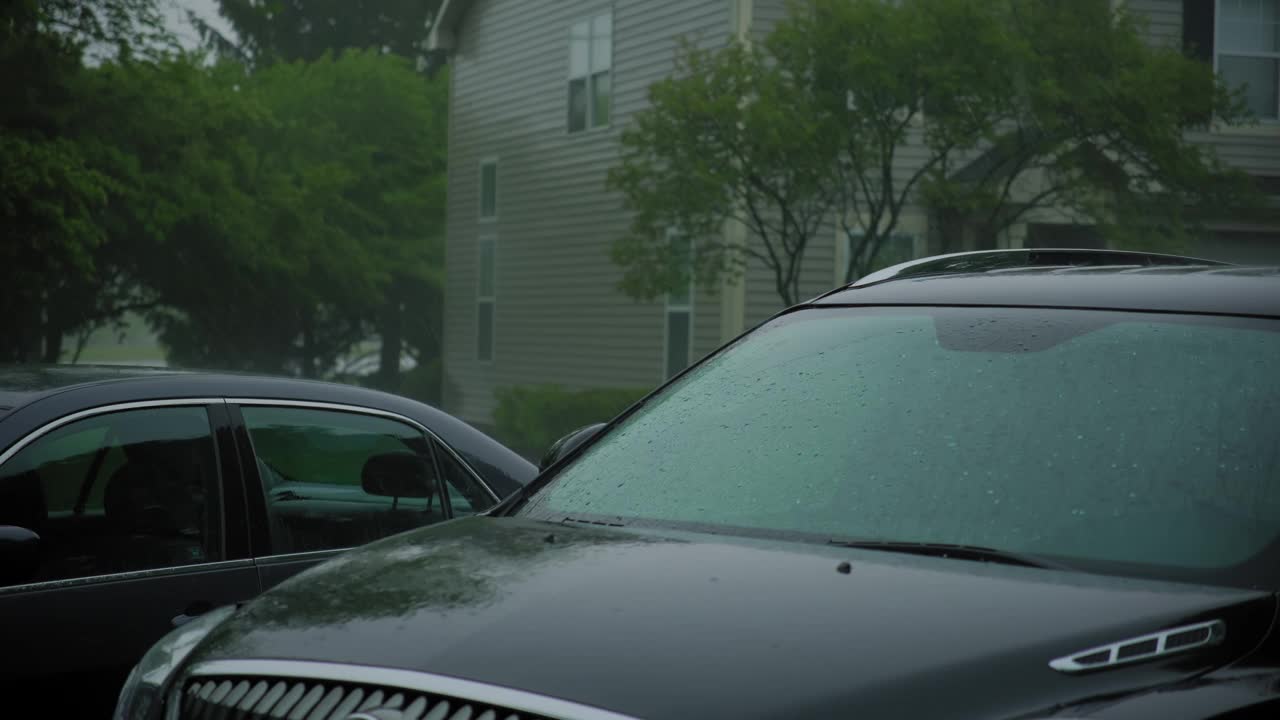 大雨暴雨。雨点落在郊区房子附近的停车场上。视频下载