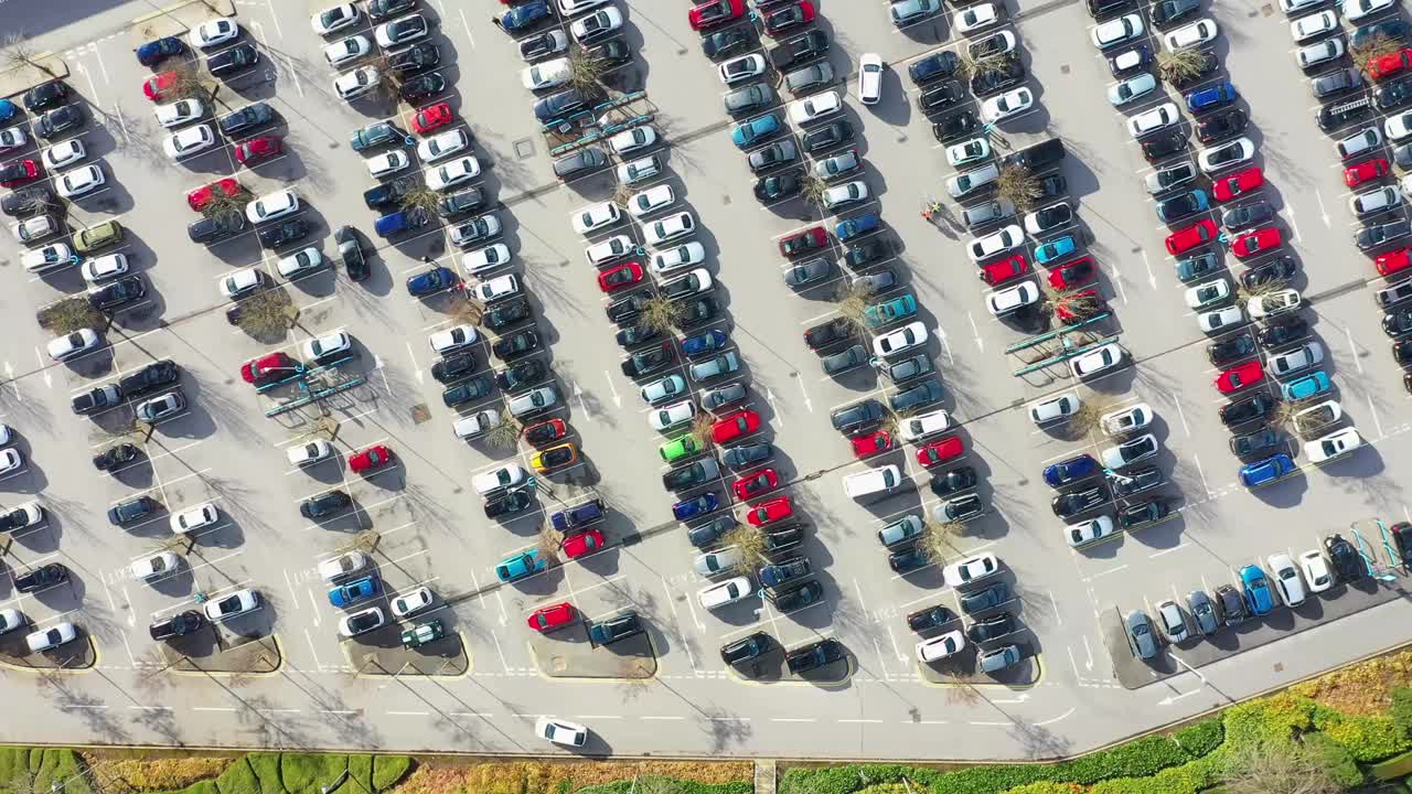 这是英国西约克郡利兹镇一个繁忙停车场的航拍画面，展示了在白玫瑰购物中心停车和寻找停车位的车辆视频下载