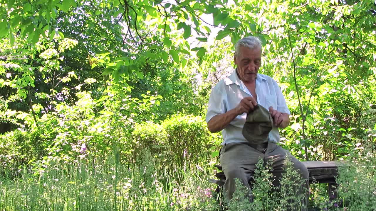 一位老人坐在大自然的木凳上视频下载