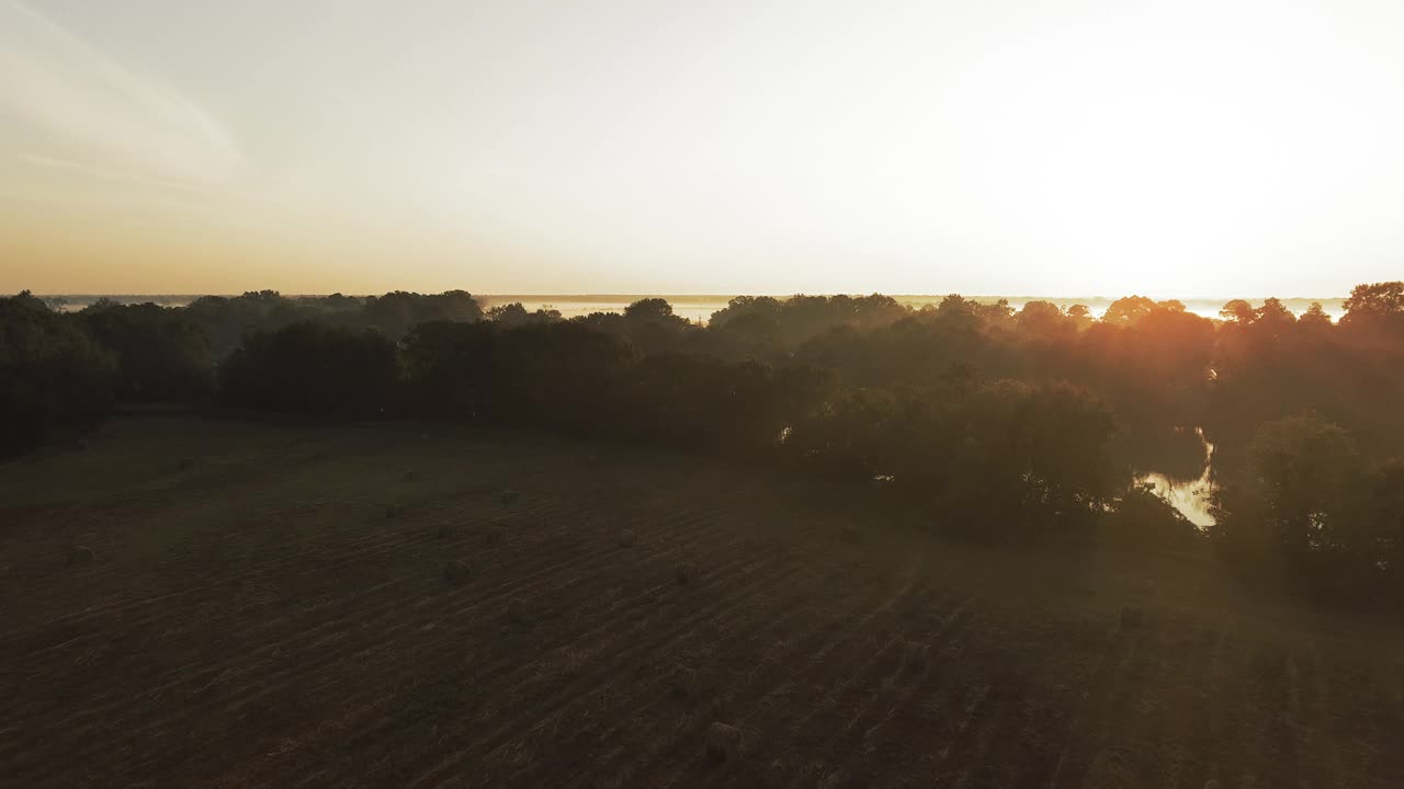 空中拍摄的宁静的河流对晴朗的天空，无人机在日落期间向后飞越绿色景观- Bayou Vista，德克萨斯州视频下载