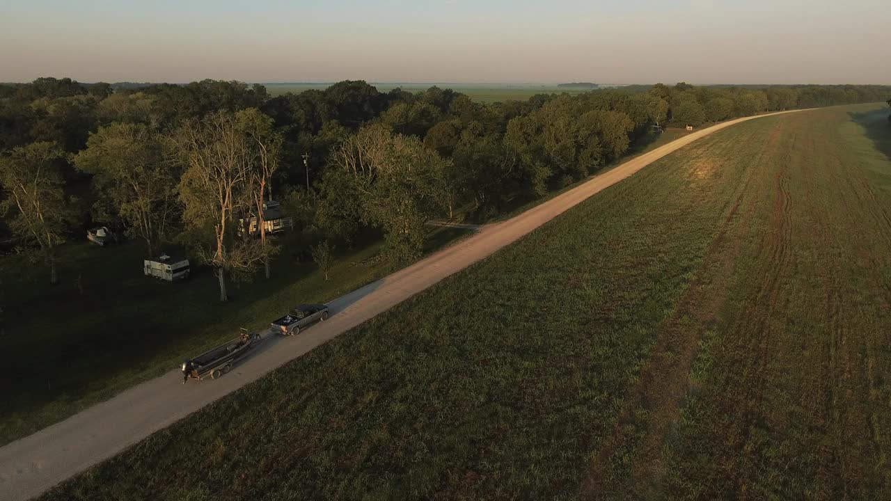 空中:皮卡车移动与船在道路上对晴朗的天空，无人机前进在绿色景观- Bayou Vista，德克萨斯州视频下载