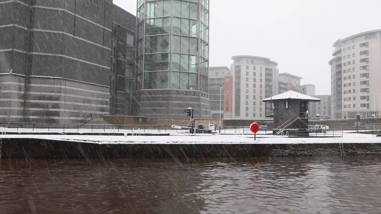 英国利兹市中心主运河的一段视频，展示了冬季下雪天的运河，背景是利兹码头和高层公寓视频下载