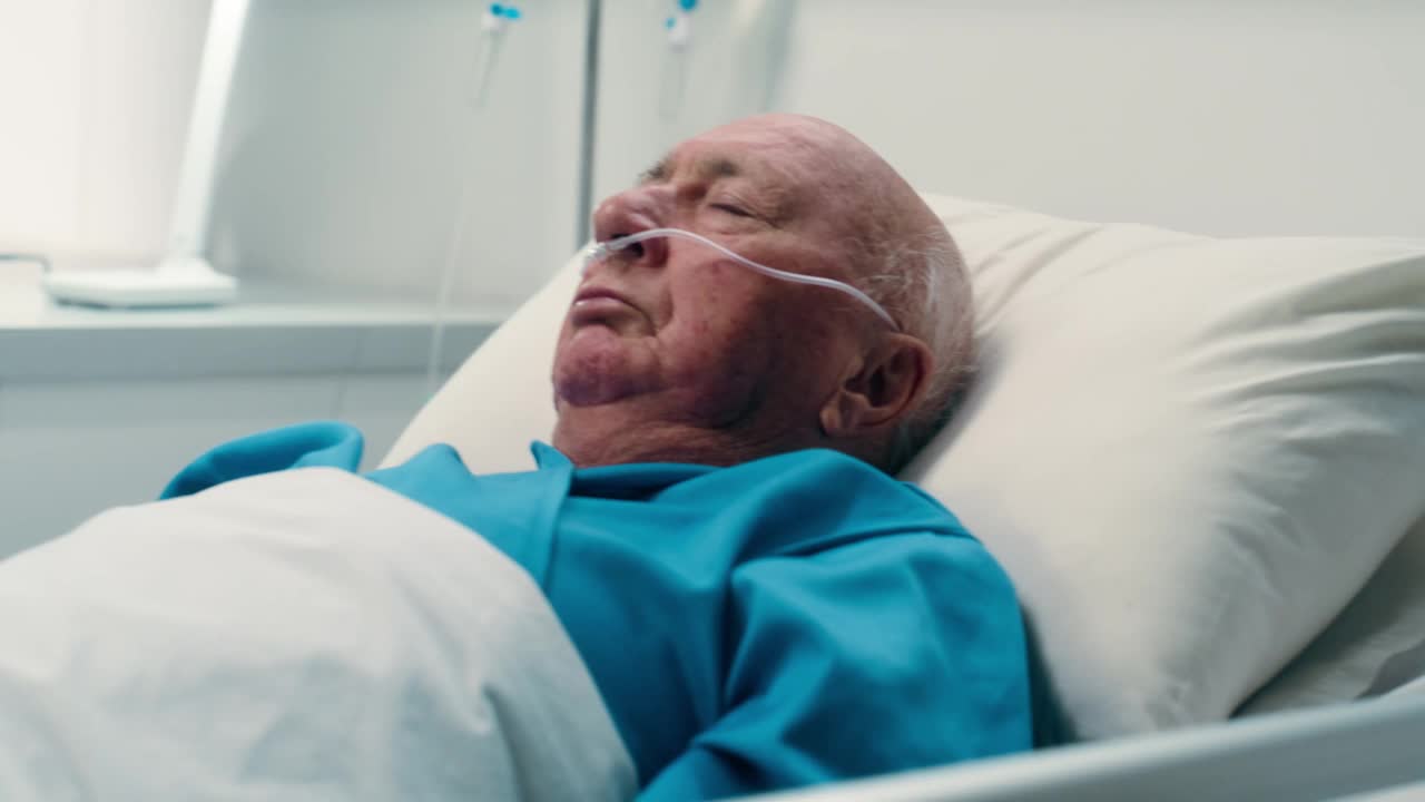 老年男子，在医院睡觉和呼吸管和床上康复后的手术或事故在诊所。休息，恢复和病人在医疗帮助下的肺部支持在ICU视频下载